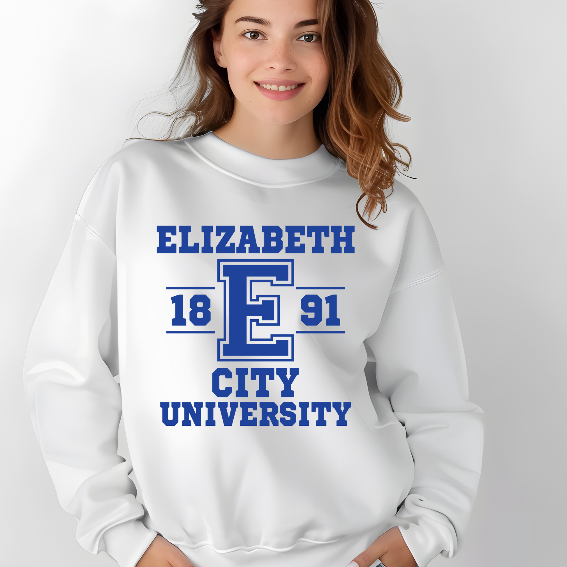 A woman wearing a white crewneck sweatshirt with a blue collegiate-style graphic that reads 'ELIZABETH 18 E 91 CITY UNIVERSITY'.