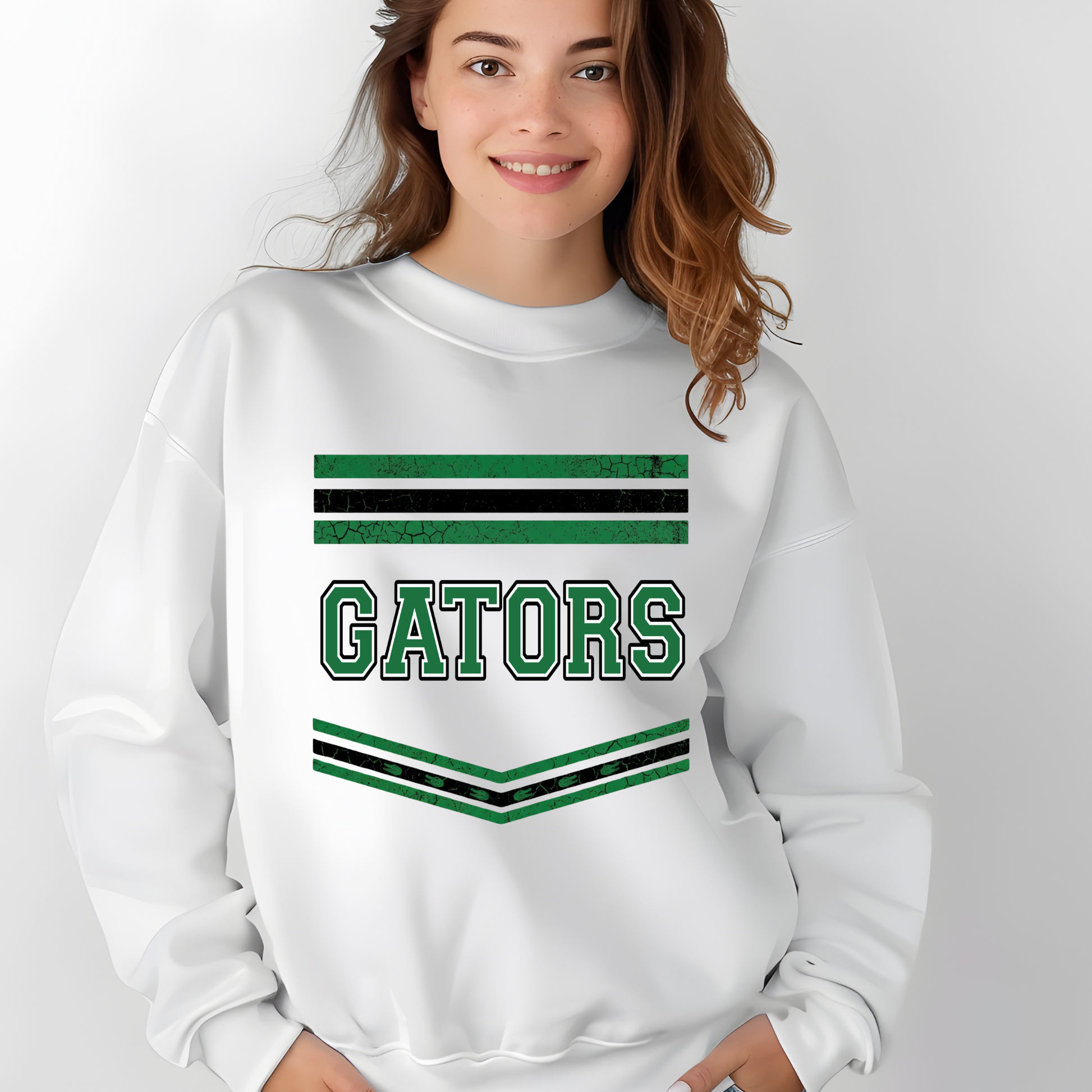 A woman wearing a white sweatshirt with green and black stripes and the word 'GATORS' printed on the front, set against a plain light gray background.