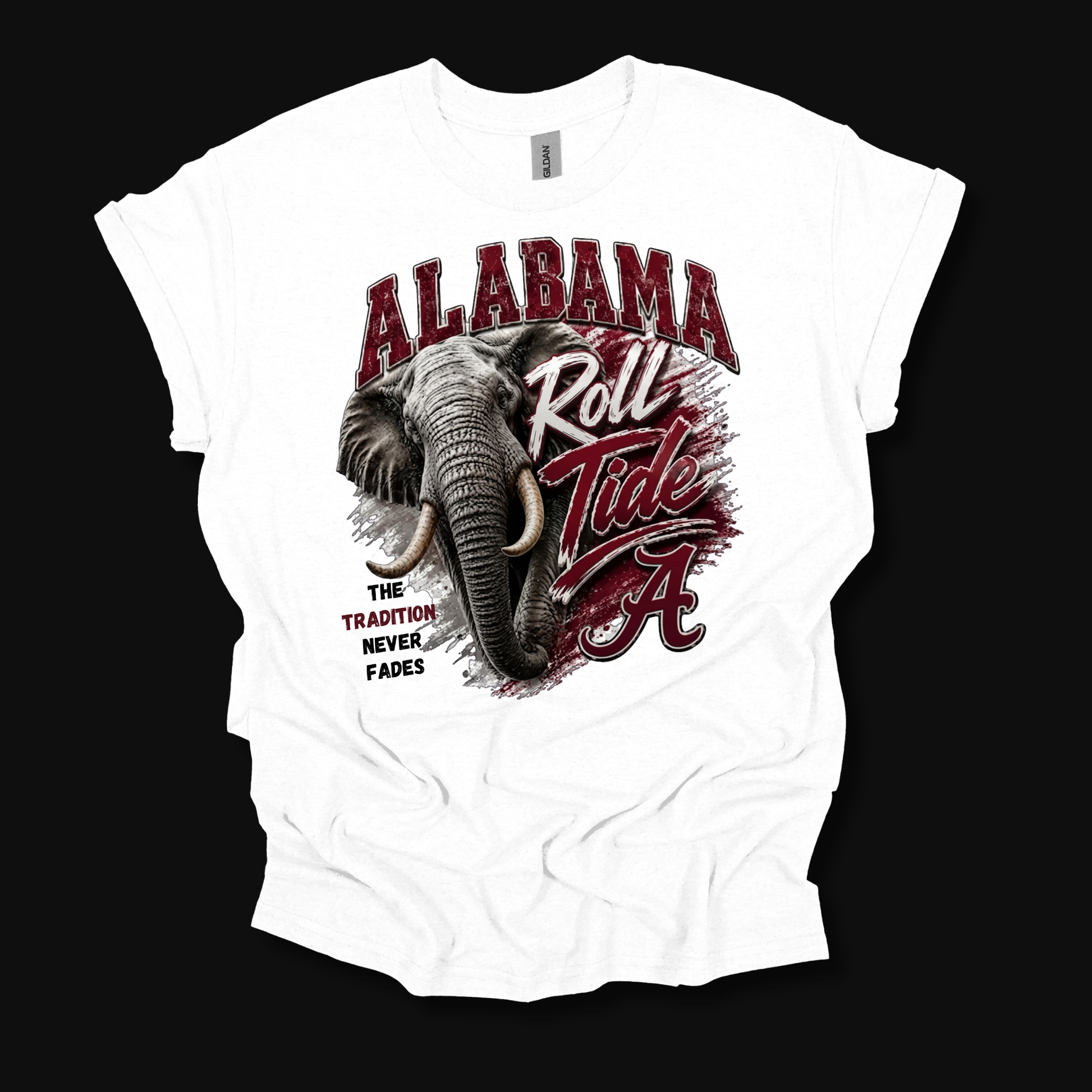 A white short-sleeve graphic t-shirt laid flat against a solid black background. The shirt features a large front print with a detailed illustration of an elephant, the text 'ALABAMA' in arched red letters, 'Roll Tide' in red and white script, and 'THE TRADITION NEVER FADES' in black.