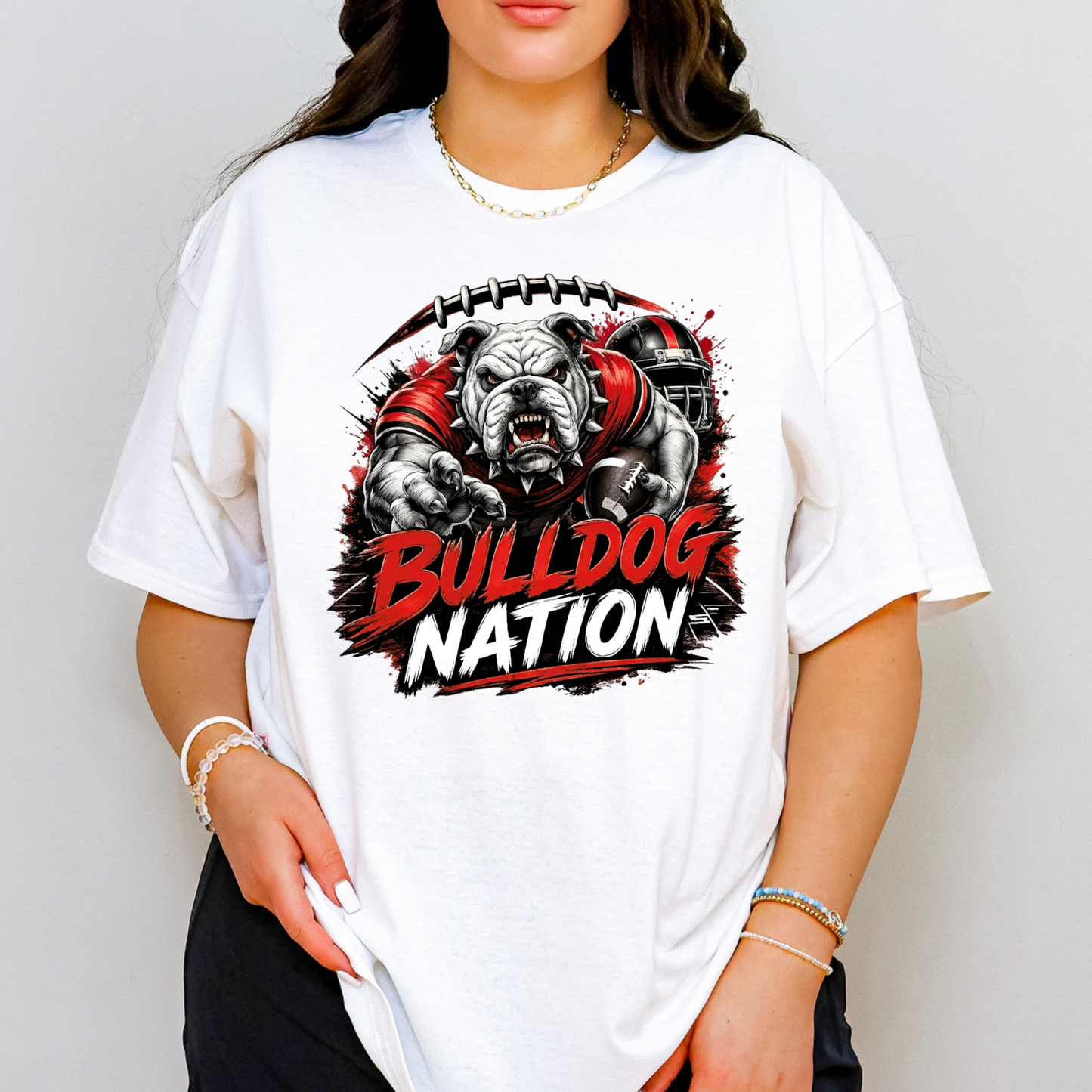 A woman wearing a white oversized graphic t-shirt featuring a bulldog mascot and the text 'BULLDOG NATION' in red and white, set against a plain light gray background.