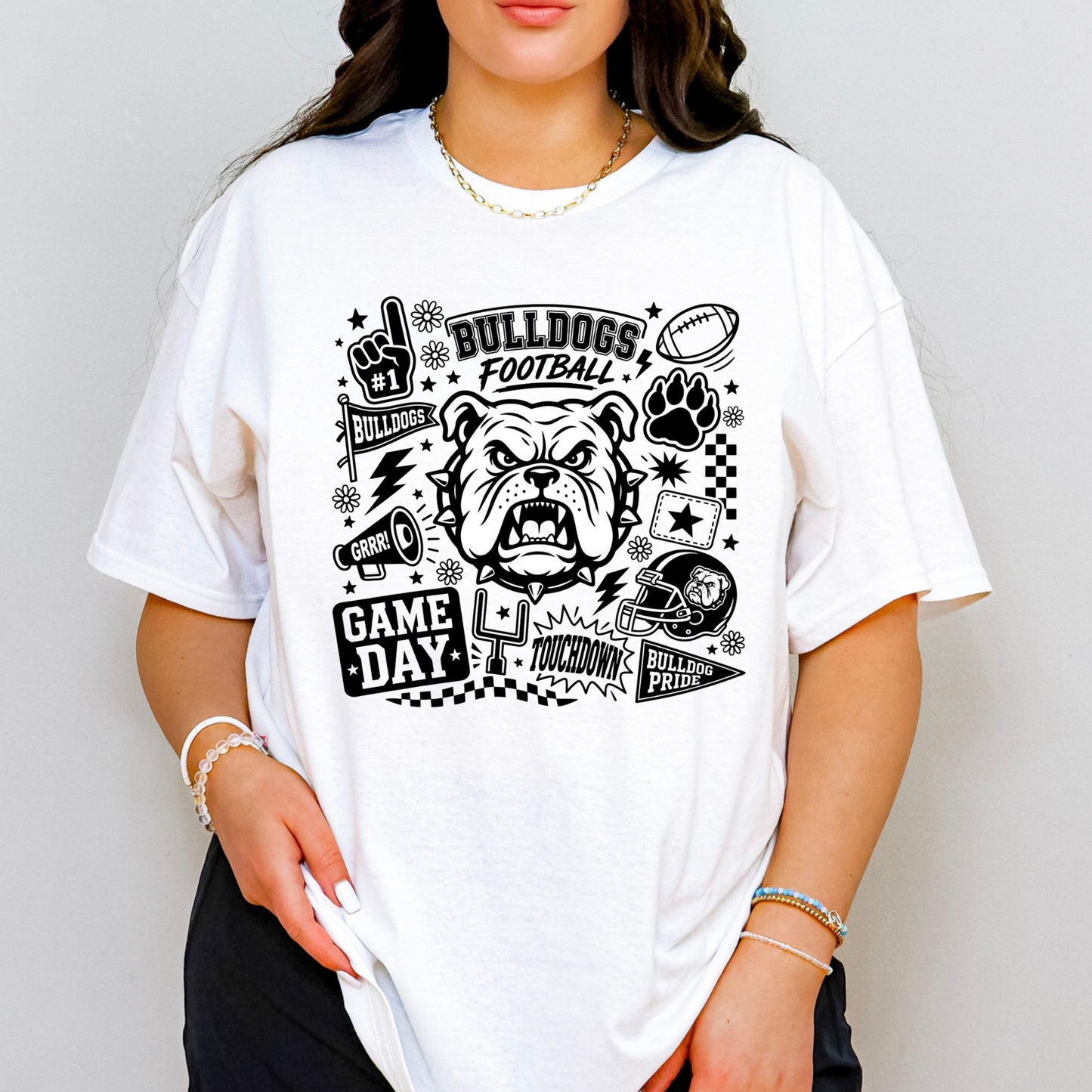 A woman wearing an oversized white graphic t-shirt with a black 'Bulldogs Football Game Day' design featuring a bulldog, football helmet, and paw print.