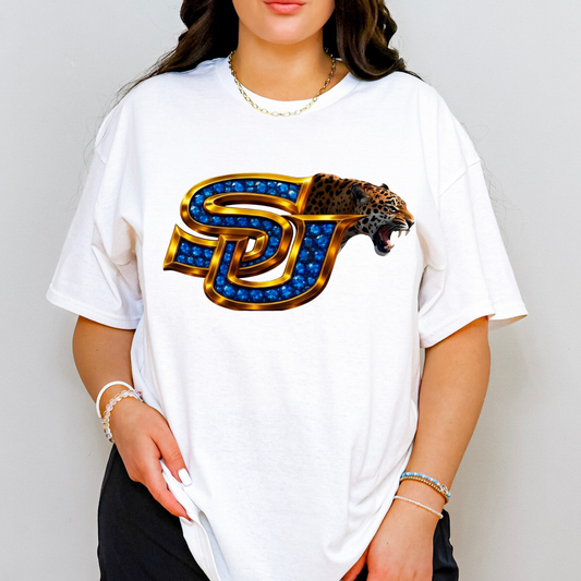 A woman wearing a white oversized t-shirt with a large graphic of the 'SJ' Utah State University logo, styled with blue gem details, gold outlines, and a leopard head on the right side. The background is a clean, neutral gray studio wall.