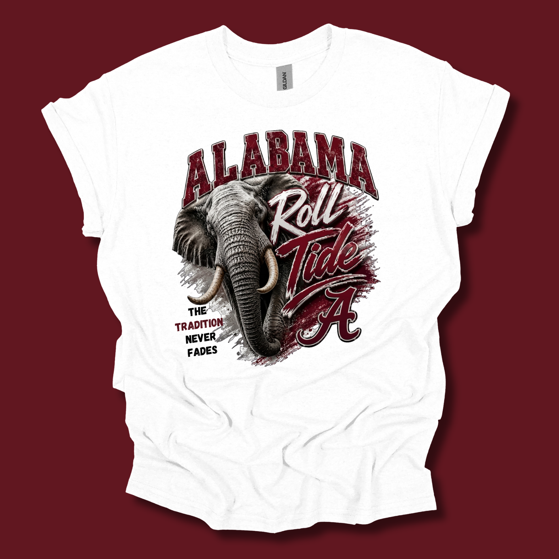 A white short-sleeve graphic t-shirt featuring an Alabama Crimson Tide elephant and 'Roll Tide' design, displayed flat against a solid dark red background.