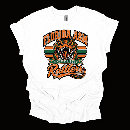 A white short-sleeve t-shirt with a graphic print of the Florida A&M University Rattlers. The design features an orange and black rattlesnake head with a green banner reading 'UNIVERSITY' and orange text reading 'FLORIDA A&M' and 'Rattlers' on a black background.