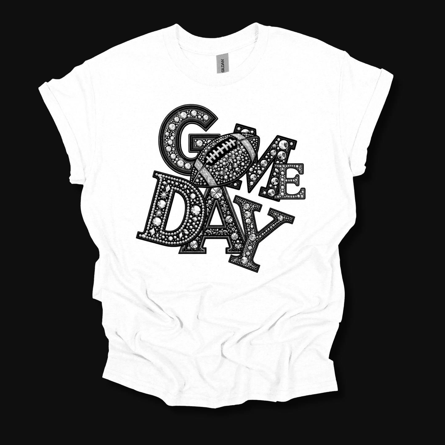 A white short-sleeve t-shirt with a black graphic reading 'GAME DAY' in a patterned font, featuring a football design inside the letter 'G', laid flat against a solid black background.