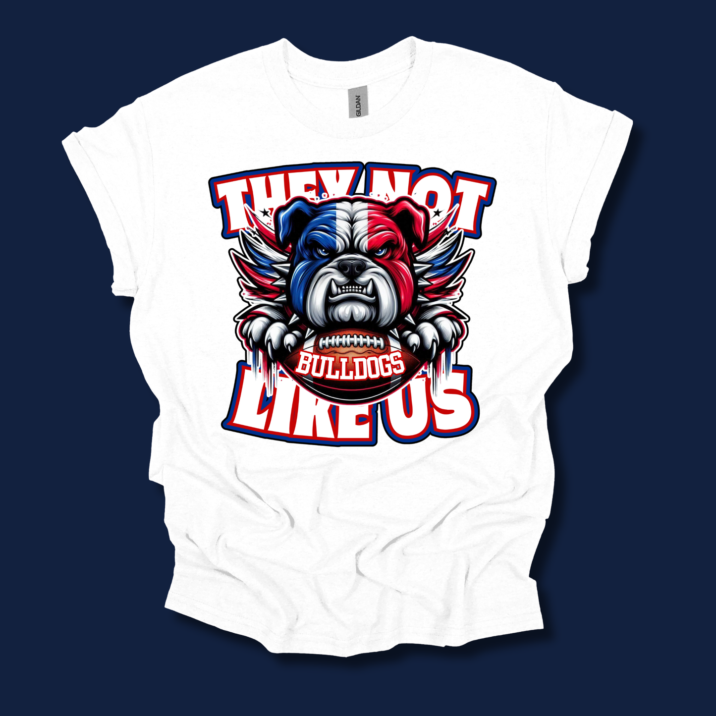 A white short-sleeve t-shirt with a graphic print of a bulldog mascot in red, white, and blue, with the text 'THEY NOT LIKE US' and 'BULLDOGS' on the front, displayed against a dark navy blue background.