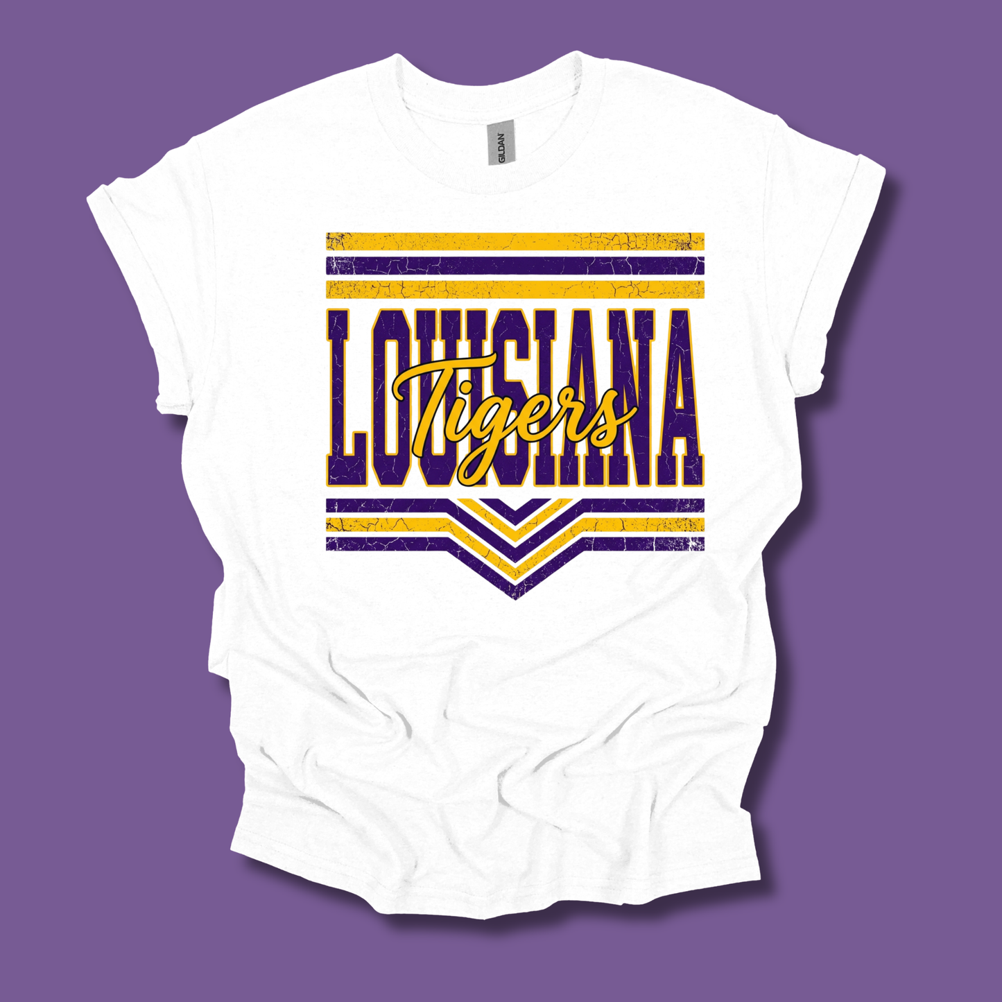 A white short-sleeve t-shirt with a distressed purple and yellow 'LOUISIANA Tigers' graphic on the front, displayed against a solid purple background.