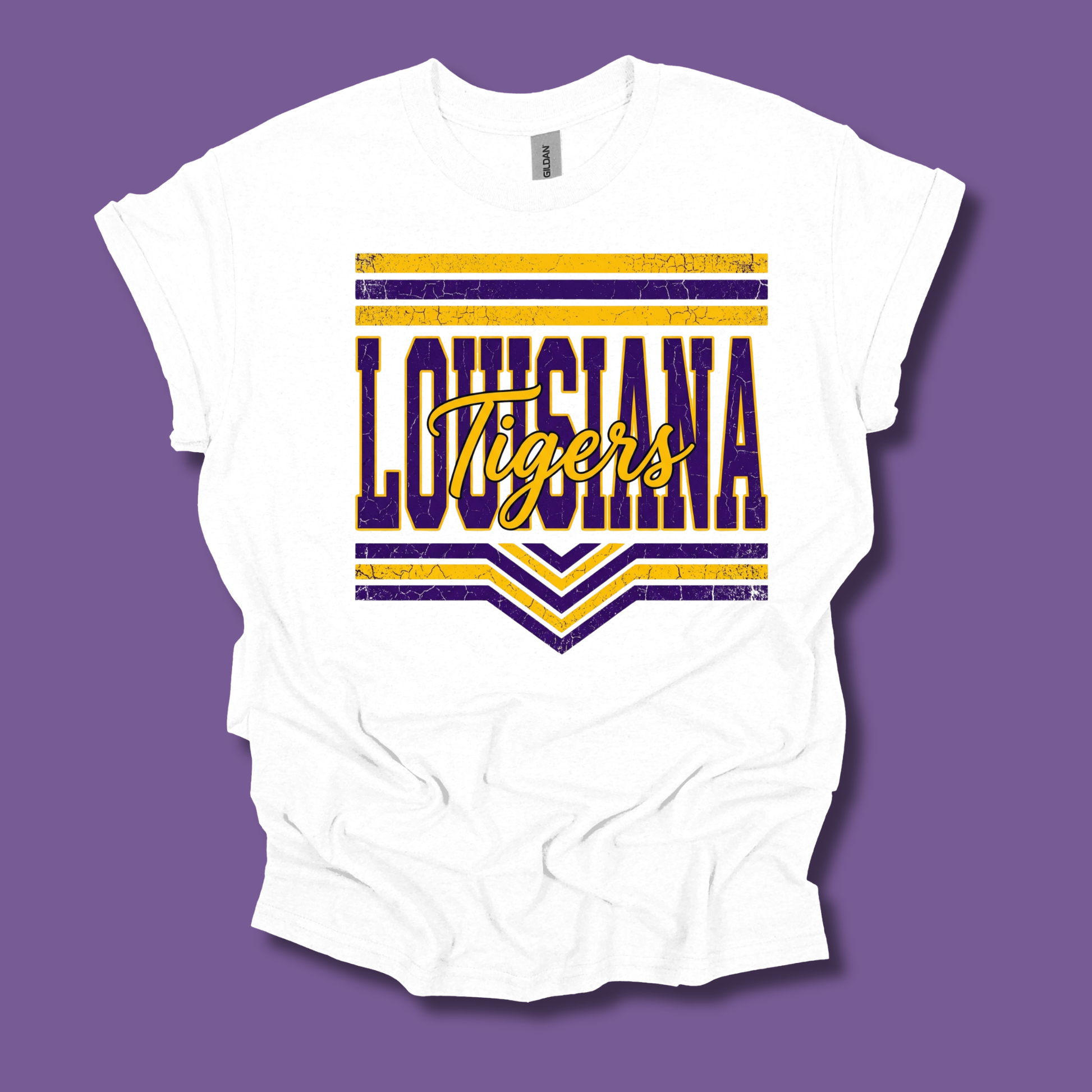 A white short-sleeve t-shirt with a distressed purple and yellow 'LOUISIANA Tigers' graphic on the front, displayed against a solid purple background.