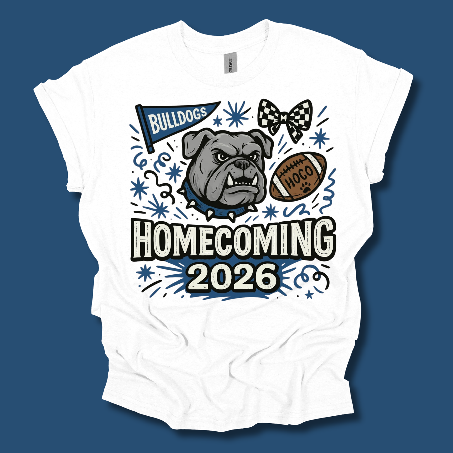 A white short-sleeve t-shirt with a graphic design on the front, featuring a bulldog, a football, a bow tie, and the text 'BULLDOGS HOMECOMING 2026' in blue, black, and brown, set against a solid dark blue background.