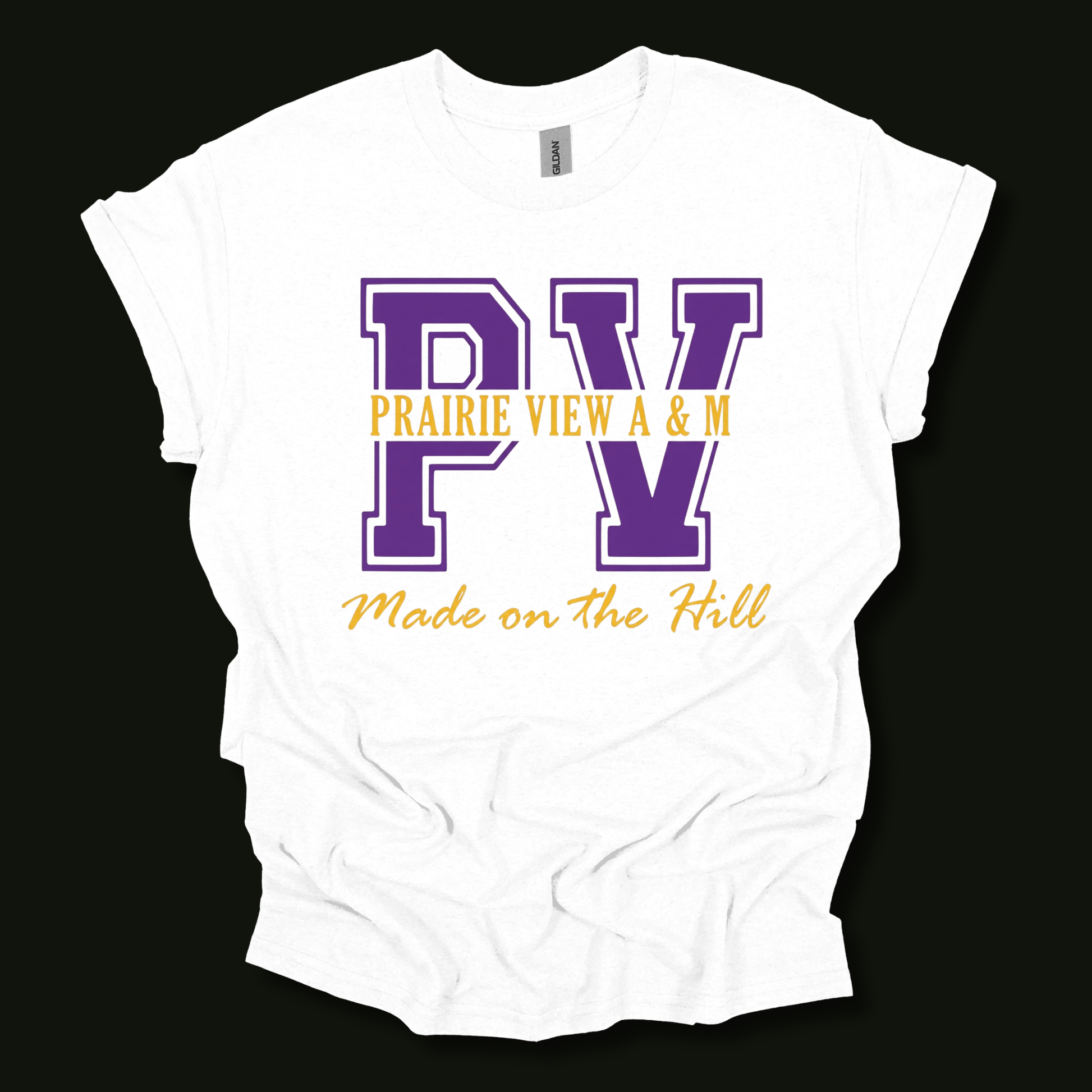 A white short-sleeve t-shirt with a purple and yellow graphic print on the front. The graphic features the letters 'PV' in purple varsity block font, with 'PRAIRIE VIEW A & M' printed in yellow across the middle, and 'Made on the Hill' in yellow script below.
