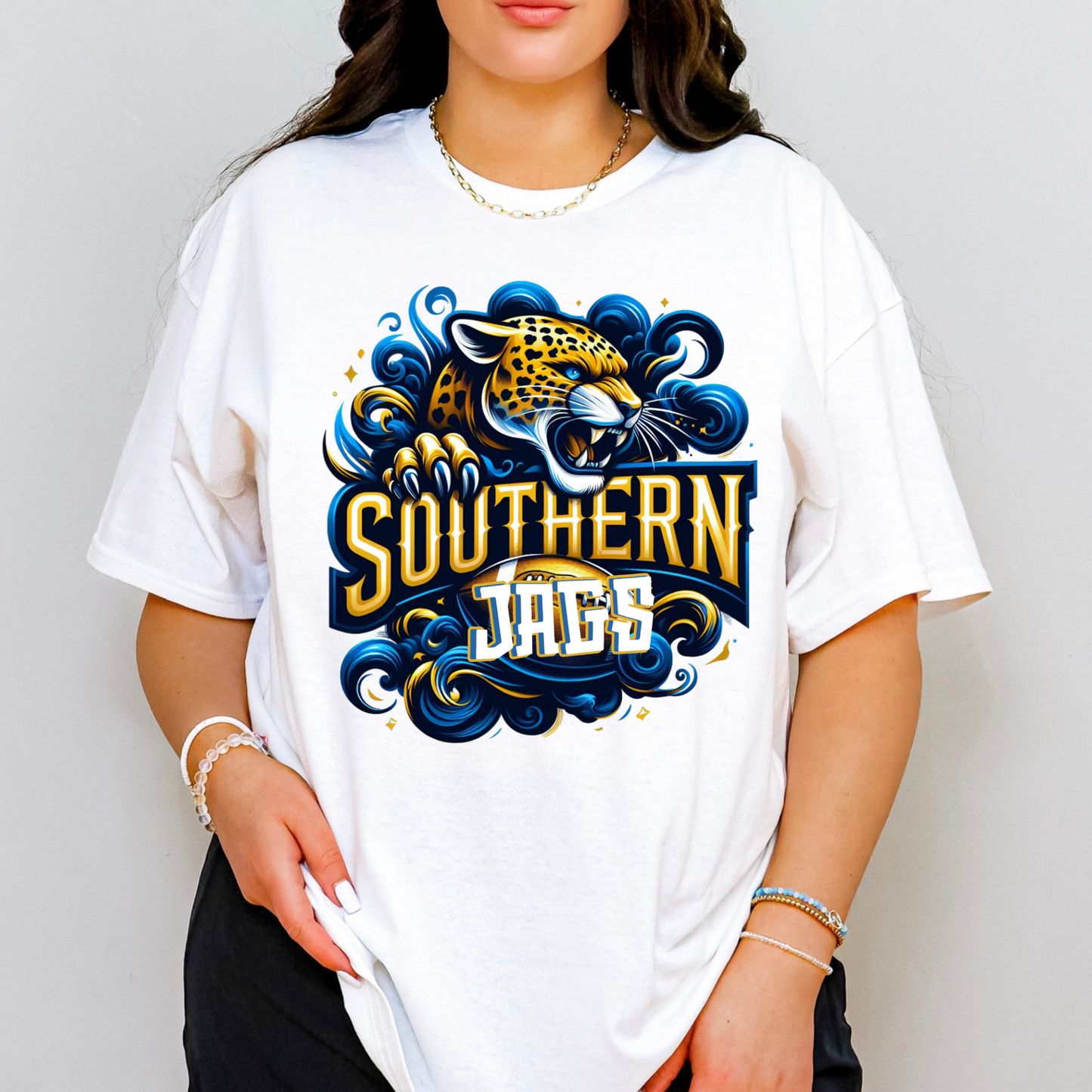 A woman wearing a white oversized graphic t-shirt featuring a stylized Southern Jaguars logo with a jaguar illustration in blue, gold, and white.