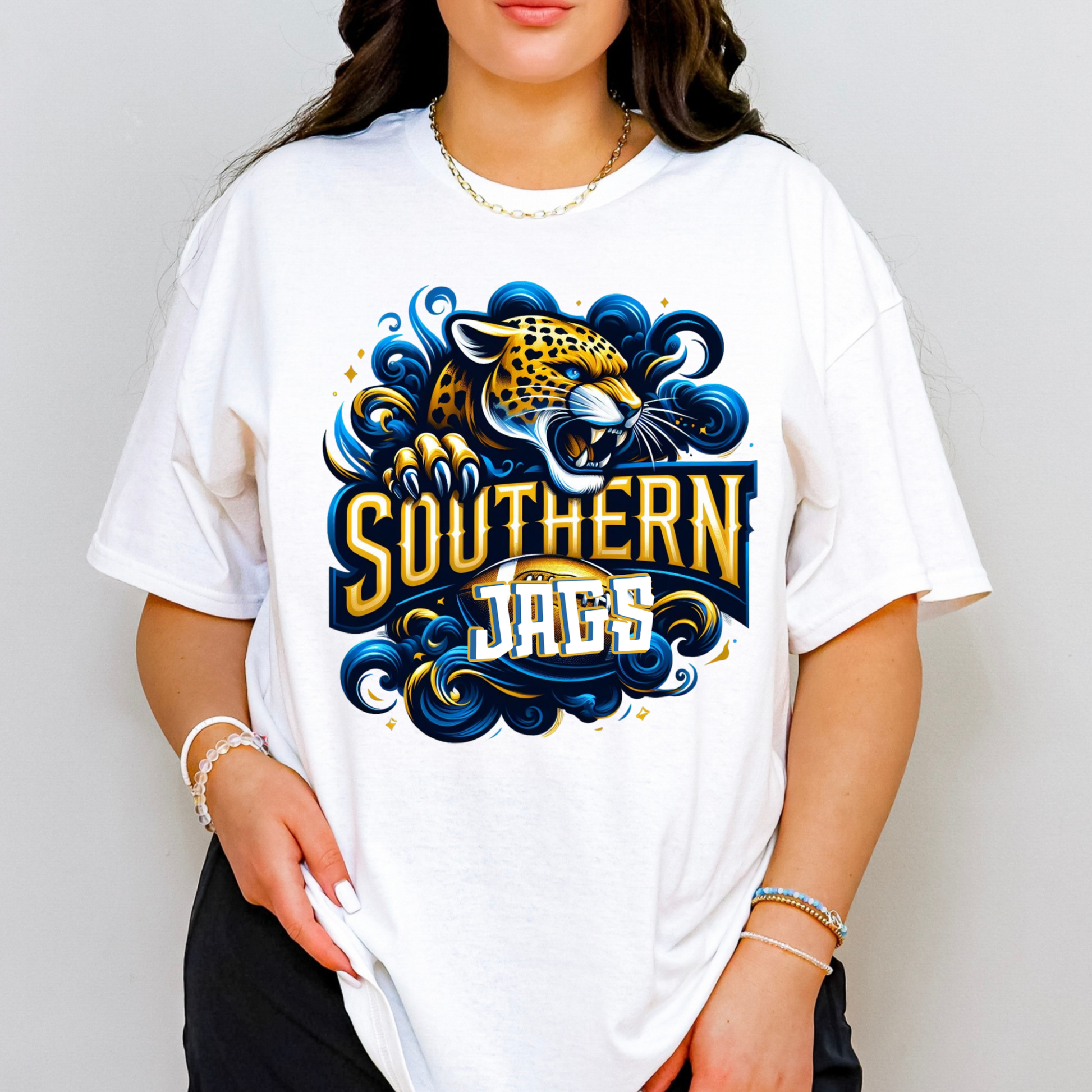 A woman wearing a white oversized graphic t-shirt featuring a stylized Southern Jaguars logo with a jaguar illustration in blue, gold, and white.