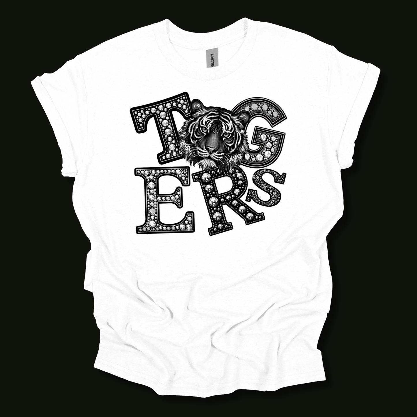 A white short-sleeve t-shirt with a black graphic print reading 'Tigers' in a diamond-studded font, featuring a tiger face integrated into the lettering, displayed against a solid black background.