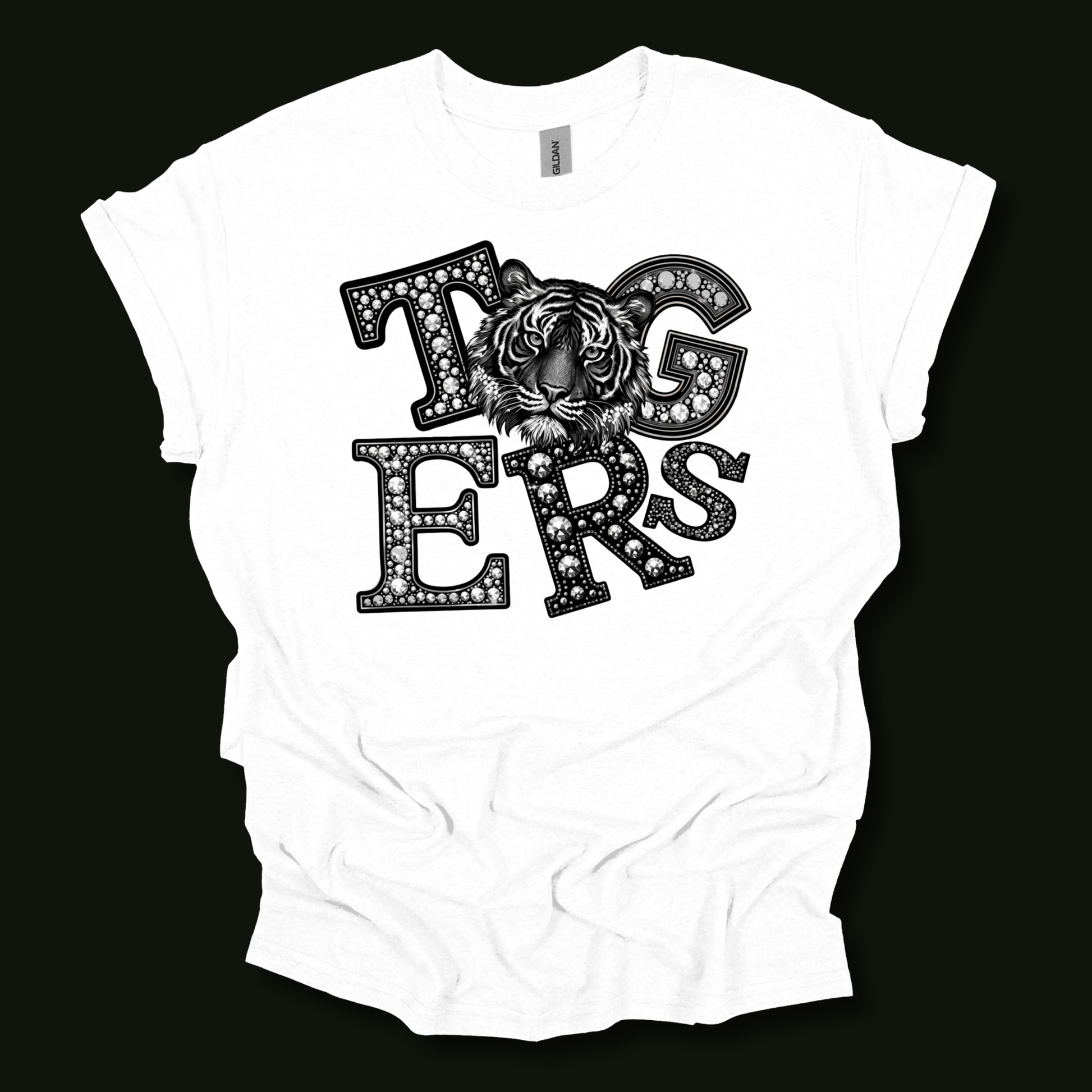 A white short-sleeve t-shirt with a black graphic print reading 'Tigers' in a diamond-studded font, featuring a tiger face integrated into the lettering, displayed against a solid black background.
