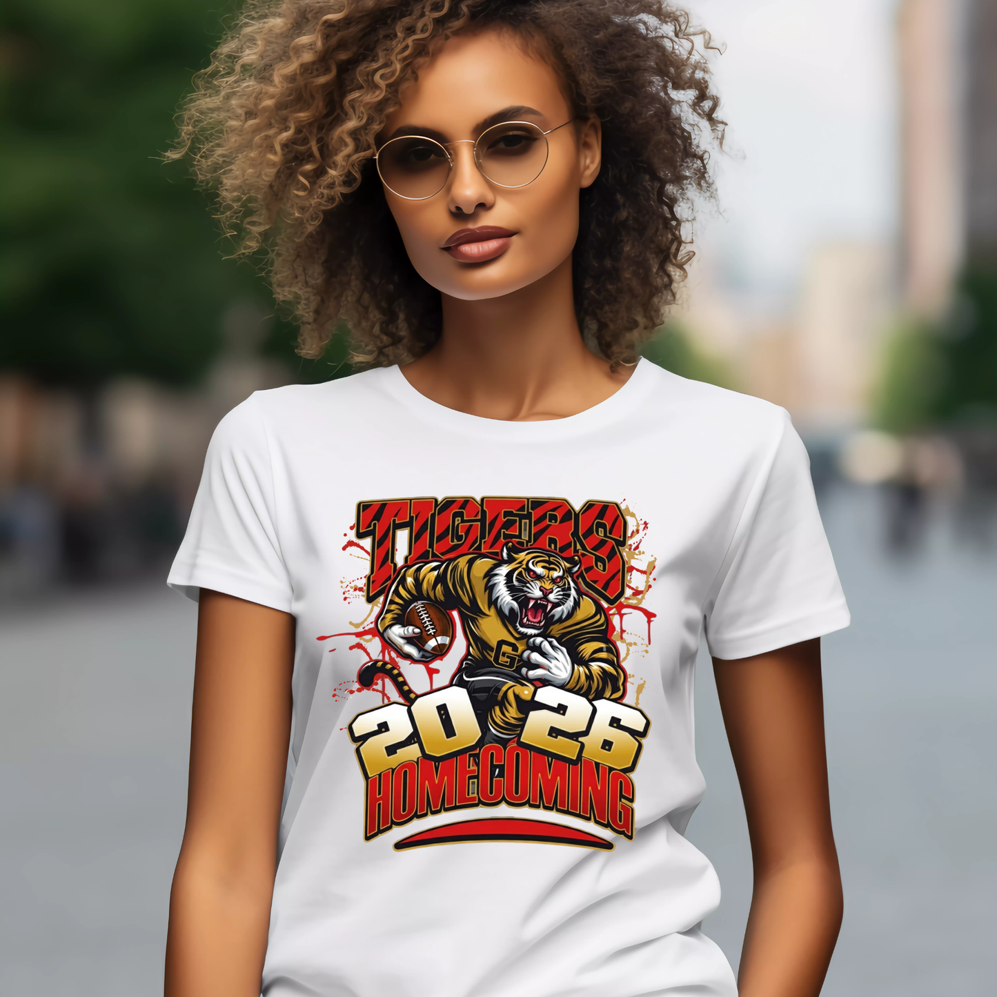 A woman wearing round glasses and a white graphic T-shirt with purple and gold text reading 'PRAIRE VIEW A&M PANTHERS I LOVE MY HBCU' and a panther mascot, photographed against a blurred outdoor street background.