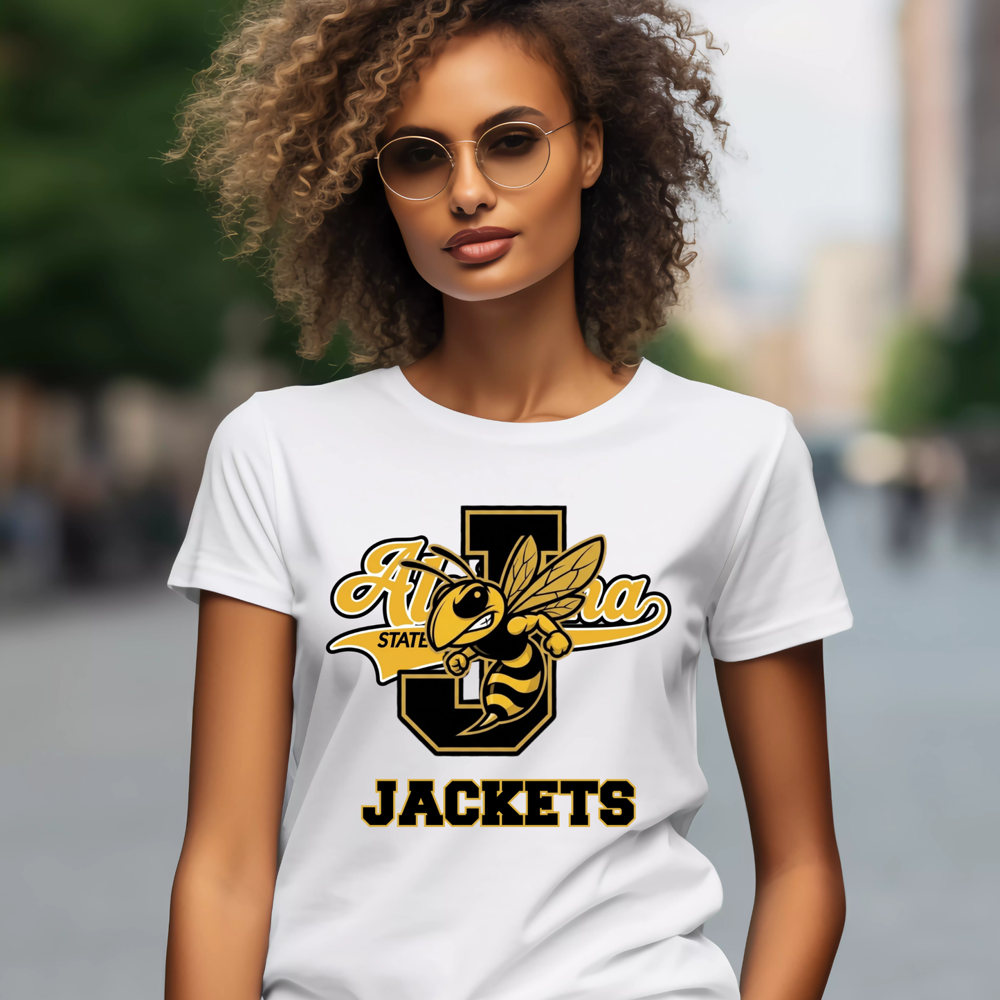 A woman wearing a white graphic t-shirt with a black and yellow 'Arizona State Jackets' design, set against a blurred outdoor street background.