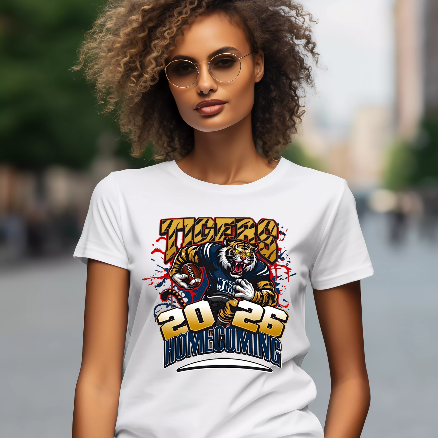 A woman wearing round glasses and a white graphic T-shirt with purple and gold text reading 'PRAIRE VIEW A&M PANTHERS I LOVE MY HBCU' and a panther mascot, photographed against a blurred outdoor street background.